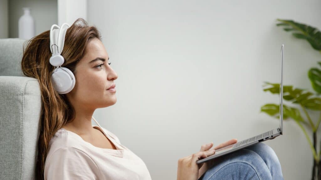 nainen kuuntelee äänikirjoja tietokoneellaan